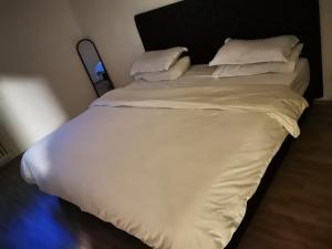 a large bed with white sheets and pillows at Short Time Stay in Schwalbach am Taunus