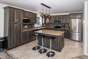 a kitchen with wooden cabinets and a island with bar stools at Domaine à Blue in Baie-Saint-Paul