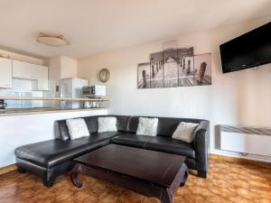 a living room with a black leather couch and a table at Apartment Les Regates-1 by Interhome in Hyères
