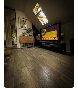 a living room with a flat screen tv and a wooden floor at Adult only , meadow escape in Coagh