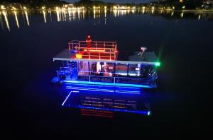 a boat with lights on the water at night at Mazurski apartament in Ostróda