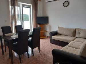 a living room with a couch and a table and chairs at Apartmani Frkic in Tisno