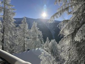 a snow covered mountain with trees and the sun in the background at Chalet Chalet Soldanella - BEL205 by Interhome in Bellwald