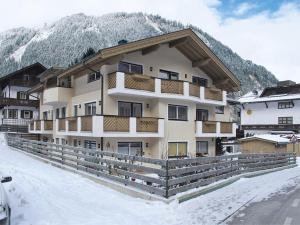 a building in the snow with mountains in the background at Apartment Rosa-2 by Interhome in Mayrhofen