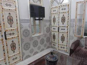 Ein Zimmer mit einem Fernseher an der Wand und bemalten Türen in der Unterkunft Le Riad Marina de Sal et Mdina in Salé + 19 Fotos