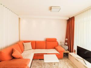 a living room with an orange couch and a tv at Apartment Cristal-4 by Interhome in Leukerbad