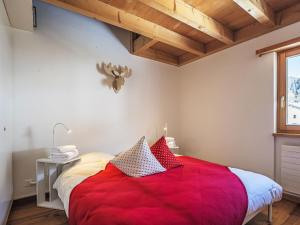a bedroom with a red bed and a window at Apartment Chesa Alossa by Interhome in La Punt-Chamues-ch