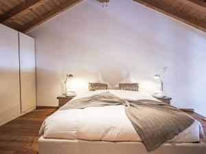 a bedroom with a large white bed with two lamps at Apartment Chesa Alossa by Interhome in La Punt-Chamues-ch +22 photos