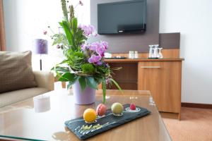 a table topped with fruit and a vase filled with flowers at Dorint Hotel am Dom Erfurt in Erfurt