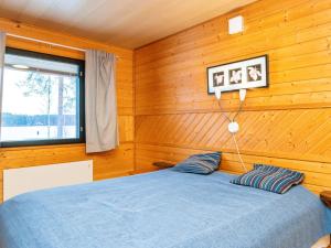 - une chambre avec un lit bleu dans un mur en bois dans l'établissement Holiday Home Huhmari 16 by Interhome, à Polvijärvi