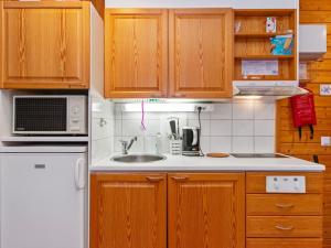 une cuisine avec des armoires en bois et un réfrigérateur blanc dans l'établissement Holiday Home Huhmari 15 by Interhome, à Polvijärvi