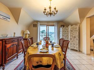 a dining room with a table and chairs and a chandelier at Apartment Le Prat-2 by Interhome in Guidel +10 photos