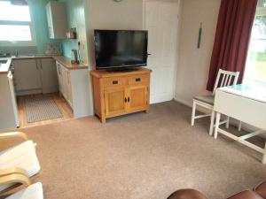 a living room with a flat screen tv on a wooden cabinet at 2 bed chalet beaches nearby in Roch