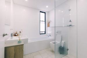 ein weißes Badezimmer mit Toilette und Badewanne in der Unterkunft ‘The Lumos’ Designer home Close to Olympic Park in Sydney + 19 Fotos
