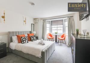 - une chambre dotée d'un lit avec des chaises orange et une table dans l'établissement Sunny & Charming Studio City Centre Nr High Street by Luxiety Stays, à Southend-on-Sea