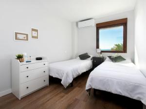a bedroom with two beds and a dresser and a window at Apartment Rinconada beachfront by Interhome in Rincón de la Victoria