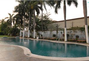 ein Pool mit Palmen und ein Gebäude in der Unterkunft The New Marrion in Bhubaneshwar