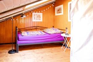 a purple bed in a room with a wooden wall at Geographer`s Cottage II in Siegsdorf