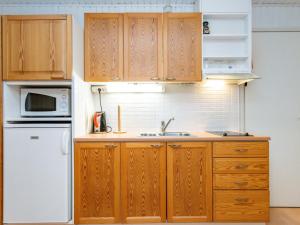 une cuisine avec des armoires en bois et un réfrigérateur blanc dans l'établissement Holiday Home Huhmari 21 by Interhome, à Polvijärvi