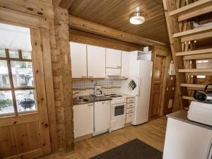 a kitchen with white appliances and wooden walls at Holiday Home Puolukka 2 by Interhome in Isnäs