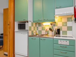 une cuisine avec des armoires bleues et un réfrigérateur blanc dans l'établissement Holiday Home Huhmari 14 by Interhome, à Polvijärvi