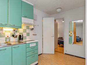 une cuisine avec des armoires bleues et un salon dans l'établissement Holiday Home Huhmari 14 by Interhome, à Polvijärvi