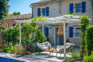a patio with a table and chairs under an umbrella at Casa Oliva by Kompas Villas in Čepljani