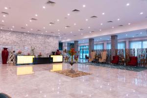 a lobby with a waiting area with chairs and a vase of flowers at Palms by Eagles Airport City, Formerly Holiday Inn in Accra
