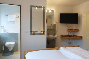 a bedroom with a bed and a bathroom with a television at Weinhaus am Schieferfels in Veldenz +65 photos