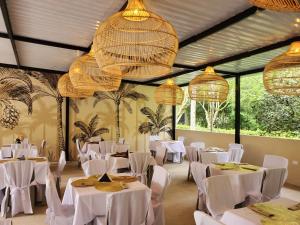 a restaurant with white tables and chairs and chandeliers at Hotel Rossé in La Vega