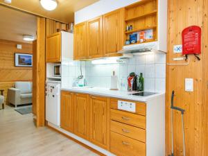 une cuisine avec des armoires en bois et un réfrigérateur blanc dans l'établissement Holiday Home Huhmari 17 by Interhome, à Polvijärvi
