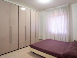シルヴィ・マリーナにあるApartment Silvi Marina Vista Mare 1 by Interhomeの白いキャビネットと紫色のベッドが備わるベッドルーム1室が備わります。