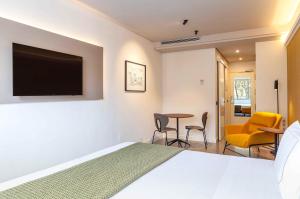 马德里别纳西班牙广场套房酒店的一间卧室，里面有一张床和一台平板电视