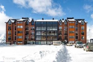 a large brick building with cars parked in a parking lot at New Gudauri Twins in Gudauri