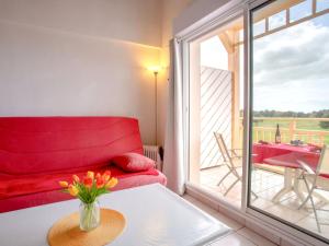 ein Wohnzimmer mit einem roten Sofa und einem Balkon in der Unterkunft Apartment L'Orée du Golf-2 by Interhome in Pornic