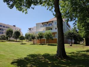 a building in a park with a tree in the foreground at Apartment Jardins de Pontaillac-7 by Interhome in Vaux-sur-Mer