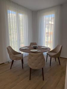 ein Esszimmer mit Tisch und Stühlen und Fenstern in der Unterkunft Apart Hotel Spa Resort Becici, Budva Апартаменты с двумя мастер-спальнями in Becici