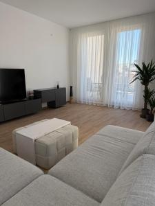 ein weißes Wohnzimmer mit einem Sofa und einem TV in der Unterkunft Apart Hotel Spa Resort Becici, Budva Апартаменты с двумя мастер-спальнями in Becici