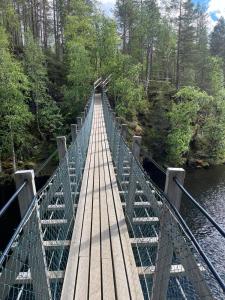 a wooden bridge over a river in a forest at Rukan Helmi A in Ruka +17 photos