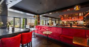 a red bar with red chairs in a room at PLAZA Premium Parkhotel Neu-Ulm in Ulm