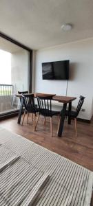 a dining room with a table and chairs and a television at Hermoso Dpto con vista Lago y Volcanes in Llanquihue
