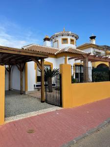 a yellow and white house with a black gate at Villa Marysol in Mazarrón