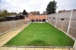a garden with a fence and green grass at Bright and Cosy Studio Apartment by Jesswood Properties Short Lets With Free Parking Near M1 & Luton Airport in Luton