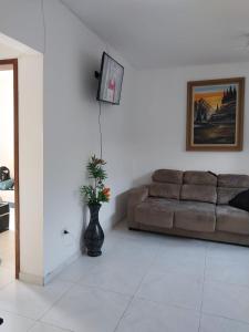 a living room with a couch and a vase with a plant at Casa na praia com 2 quartos in Itanhaém