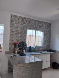 a kitchen with a granite counter top and a window at Apartamento na praia 2 qt com quintal e churrasqueira in Itanhaém +7 photos