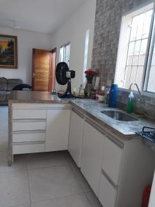 a kitchen with white cabinets and a sink and a window at Apartamento na praia 2 qt com quintal e churrasqueira in Itanhaém