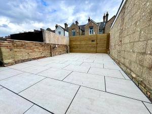 a large courtyard with a brick wall and a building at Stunning 4-Bedroom Home - 10 mins to Sandbanks Beach in Poole