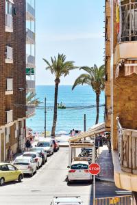 a street with cars parked on the beach with palm trees at Home&Holiday Andalisa in Torrevieja