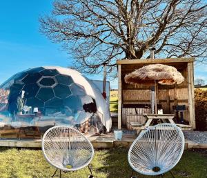 two chairs and an umbrella and a table and a tent at Deerstone Glamping-Pinhaw Beacon dome Hot tub in Earby