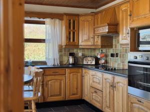 a kitchen with wooden cabinets and black counter tops at Stargazers Cottage in Doolin +7 photos